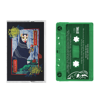 A transparent green cassette from The Home Team, labeled "Slow Bloom," rests beside cover art showing a masked figure in a blue robe amid yellow flowers on a dark background.