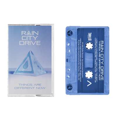 Rain City Drive’s blue tint cassette comes in a clear norelco box, displaying “RAIN CITY DRIVE” and “THINGS ARE DIFFERENT NOW” over an icy pyramid with a water droplet. The transparent tape with white text is perfect for collectors.