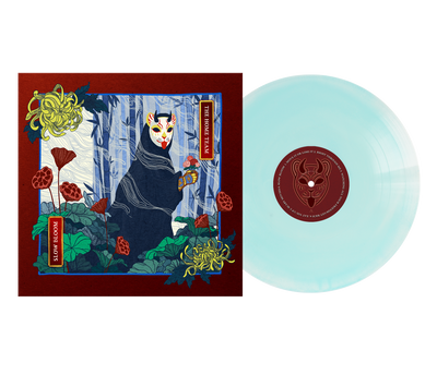 A translucent Opaque White & Transparent Electric Blue vinyl by The Home Team sits beside its album cover, showing an illustrated figure in a forest with a fox mask and dark cloak, surrounded by red and yellow flowers and green leaves.
