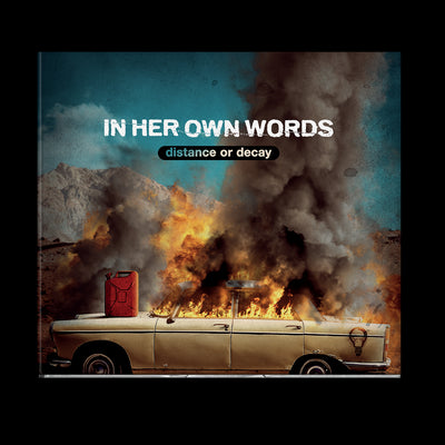 Image of the in her own words, distance or decay album artwork. It says In her own words, distance or decay in white and transparent letters in the center. the album cover is an image of an old car with a gas can on the hood, the car windows and roof of the car up in flames. There are mountains in the distance and a blue sky above the car.