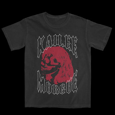 Photo of a black tshirt against a transparent background. In white outline text reads "kailee morgue". In between the words Kailee and Morgue is an image of a red side profile of a skull with hair.