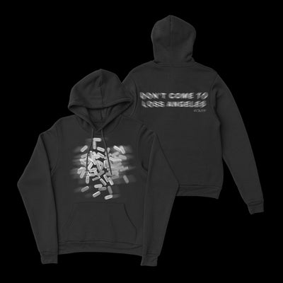 Image of the front and back of a black hoodie against a transparent background. The front of the hoodie features a blurred graphic of white pills. The back of the hoodie in blurred white text says don't come to loss angeles. 