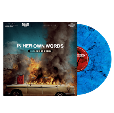 Image of a vinyl sleeve and blue and black smoke design vinyl against a transparent background. The Vinyl sleeve says In her own words, distance or decay in white and transparent letters in the center. the album cover is an image of an old car with a gas can on the hood, the car windows and roof of the car up in flames. There are mountains in the distance and a blue sky above the car.